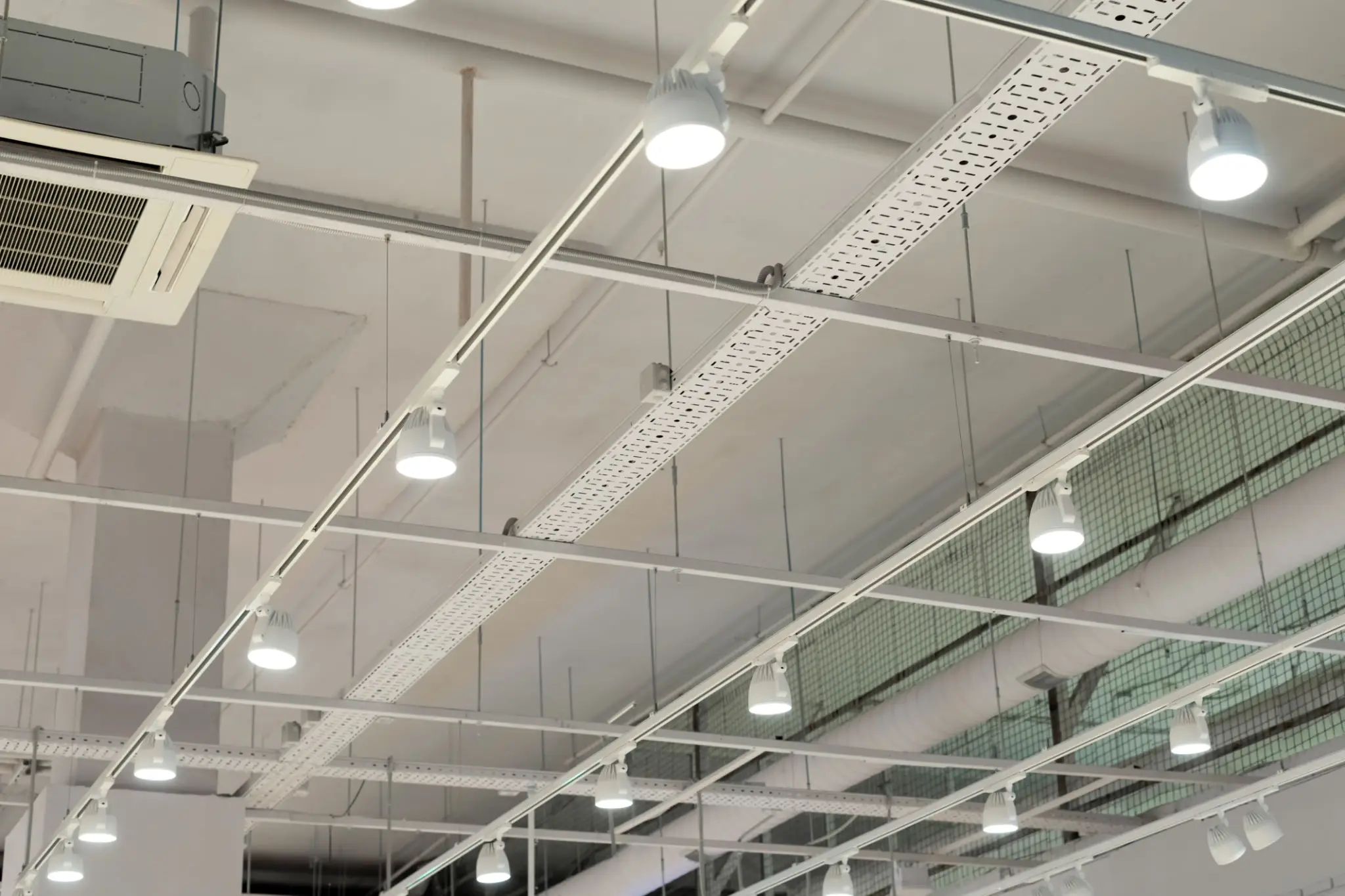 Modern ceiling with white beams and hanging lights in an indoor space.