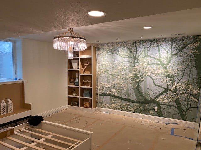 Cozy room with a tree mural and a built-in bookshelf under soft lighting.
