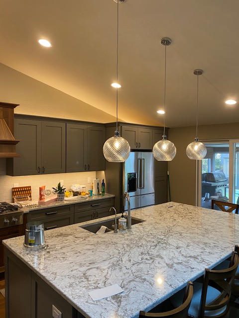 Modern kitchen with marble island and pendant lights.